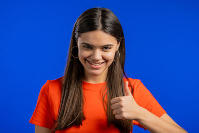 Portrait of a smiling young woman against blue background