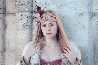 Portrait of beautiful young woman standing against wall