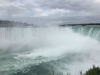 Scenic view of waterfall against sky