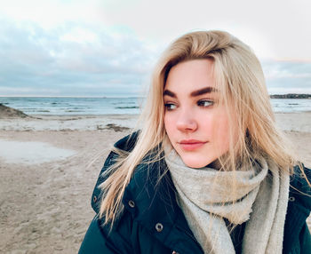 Portrait of beautiful woman on beach against sky