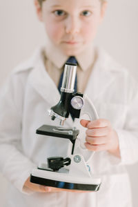 Child in labcoat holding a science microscope