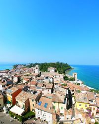 Aerial view of townscape by sea against clear blue sky