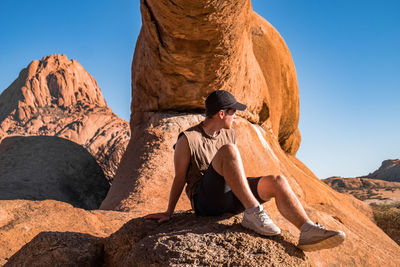 Man looking away while sitting on rock formation