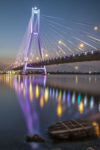 Illuminated bridge over river against sky at night