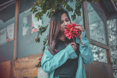 Close-up of young woman standing by flowers