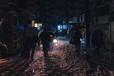 Rear view of people walking on street at night