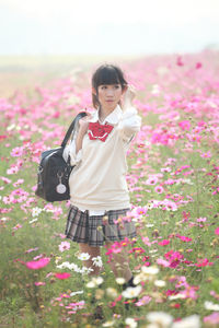 Woman standing amidst flowering plants on field against sky