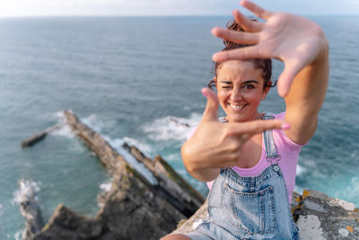 Portrait of young woman standing by sea