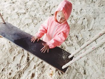Cute girl standing by swing on sand at beach