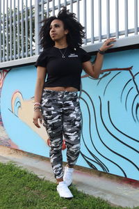 Portrait of young woman standing against graffiti wall