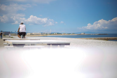 Rear view of man on beach against sky