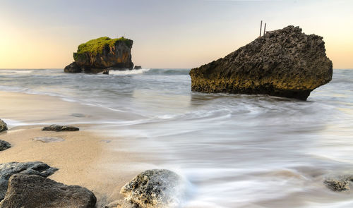 Scenic view of rocks in sea against sky