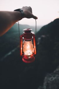 Close-up of person holding illuminated electric lamp