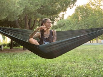 Young woman sitting on field against trees