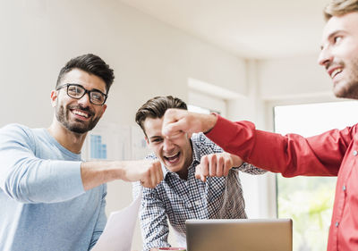 Three young professionals celebrating in office