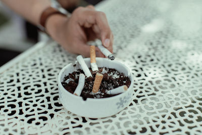 Hand holding cigarette on table