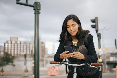 Young woman using smart phone in city