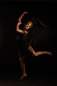 Portrait of young woman standing against black background