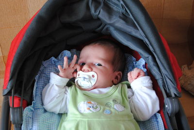 Portrait of cute baby boy sucking pacifier in stroller