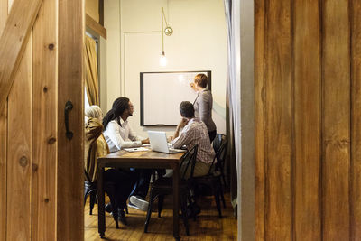 Businesswoman writing on whiteboard in creative office