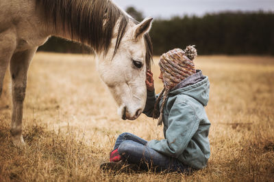 Young girl touching white horse head in field