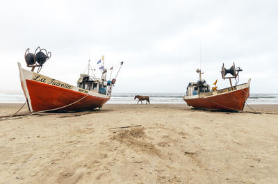 Boat moored on beach against sky