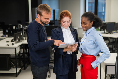 Colleagues discuss work. african young woman, caucasian man and red-haired caucasian woman