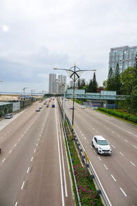 Vehicles on road against sky in city