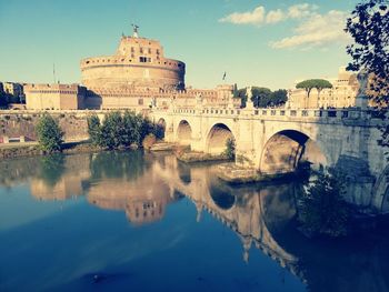 Arch bridge over river against buildings