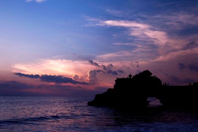 Silhouette rocks by sea against sky during sunset