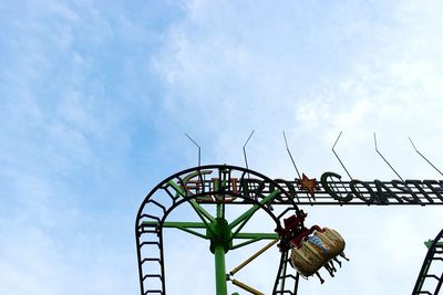 Low angle view of ferris wheel against cloudy sky