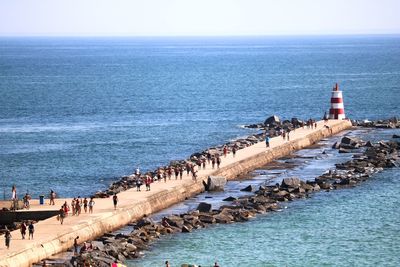 Group of people on beach by sea against sky