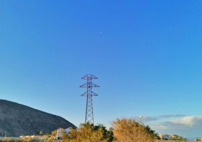 Low angle view of telephone pole against clear blue sky