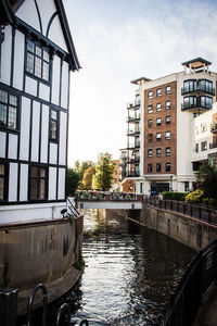 Canal amidst buildings in city against sky