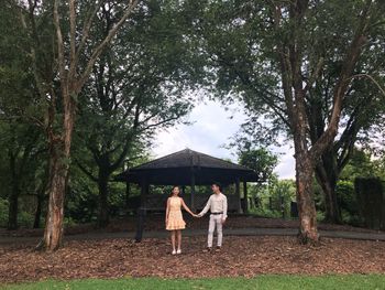 People standing by tree trunk amidst plants