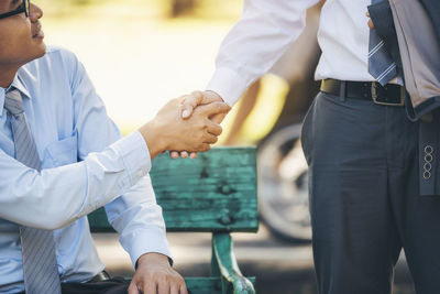 Midsection of colleagues shaking hands outdoors