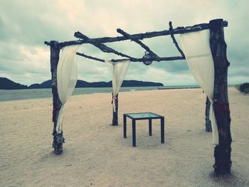 Wooden posts on beach against sky