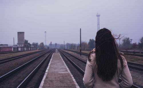 Rear view of people walking on railroad track