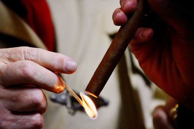 Cropped hands of person igniting cigar