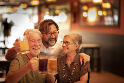 Cheerful couple with son holding drink at restaurant