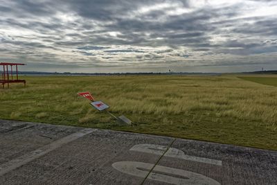 Scenic view of grassy field against cloudy sky