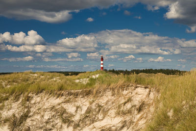 Lighthouse on street amidst buildings against sky