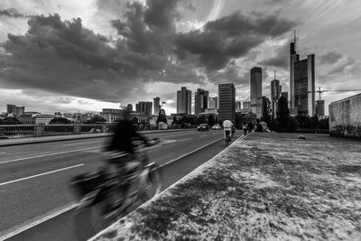 Blurred motion of man and cityscape against sky