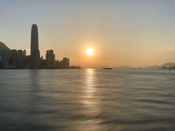 Scenic view of sea by buildings against sky during sunset