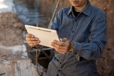 Midsection of man using mobile phone