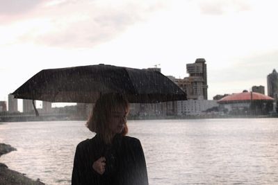 Woman standing in rain against sky