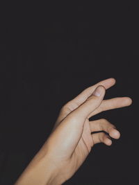 Close-up of hand gesturing against black background