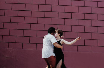 COUPLE STANDING AGAINST WALL