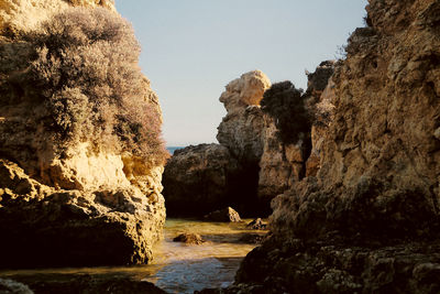 Rock formations by sea against clear sky