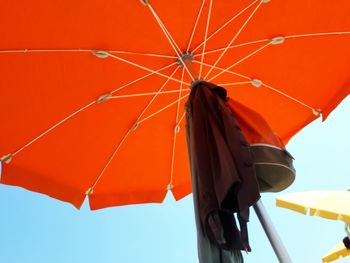 Low angle view of red umbrella against clear blue sky